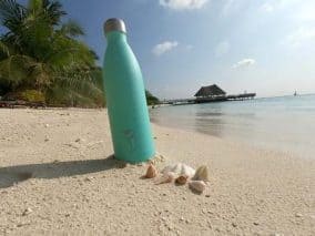 The pictures contains an insulated water bottle and a few shells on a sandy beach in The Maldives. A Chilly bottle is a must have travel item you need to add to your ultimate Maldives packing list, not having it is one of the worse mistakes to avoid in the Maldives.
