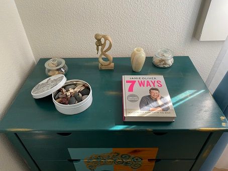 My nice and creative way to display travel souvenirs - this small piece of furniture with a rock and shell collection from various beaches around the world, a wooden statue from Bali and a cooking book from Lisbon.